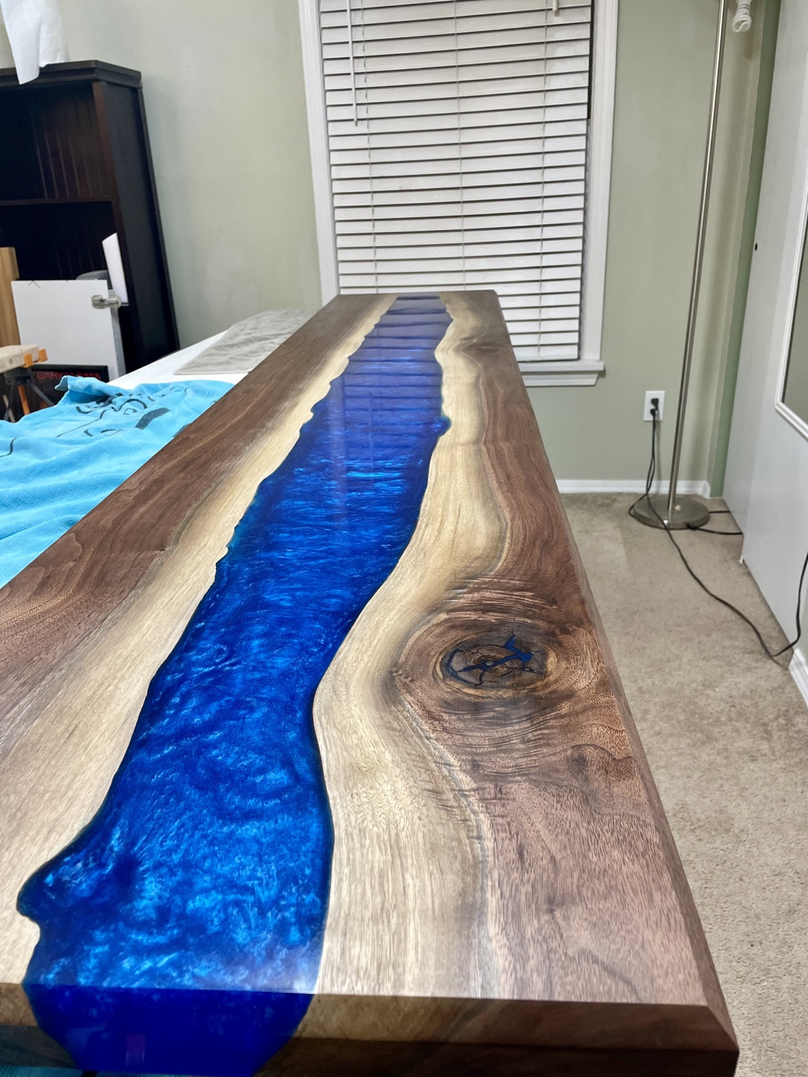 Detail of the completed tabletop showing walnut sapwood, live edge, and blue resin